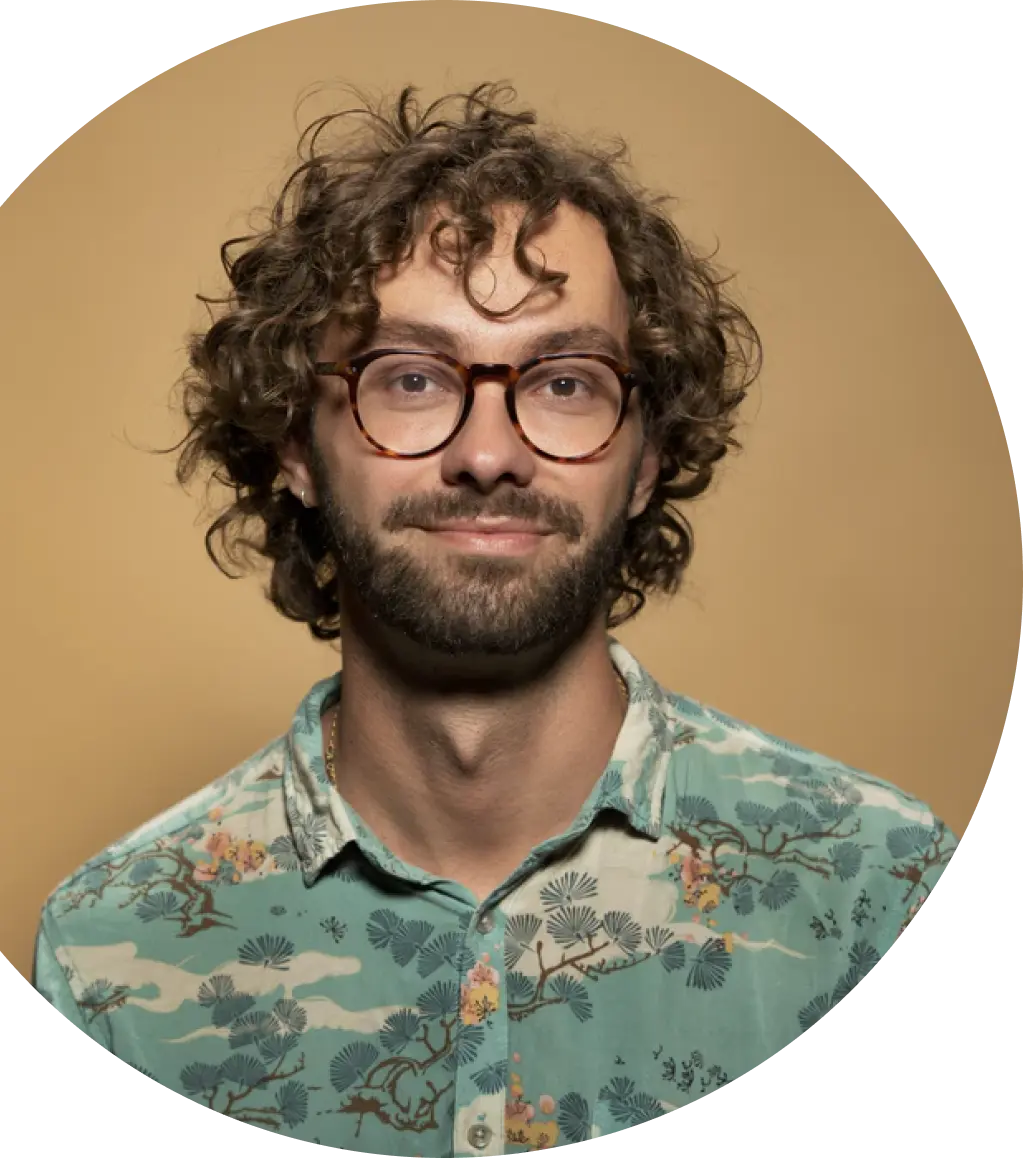 Smiling man with curly hairs, shirt, glasses on brown background