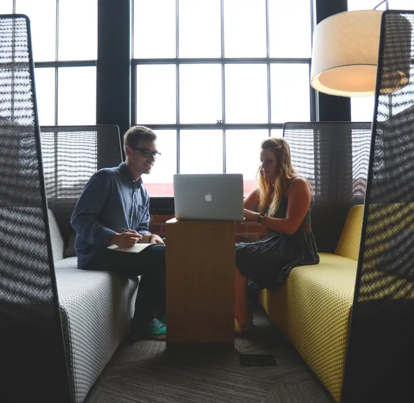 a guy and a girl are sitting on the couch and looking at a laptop