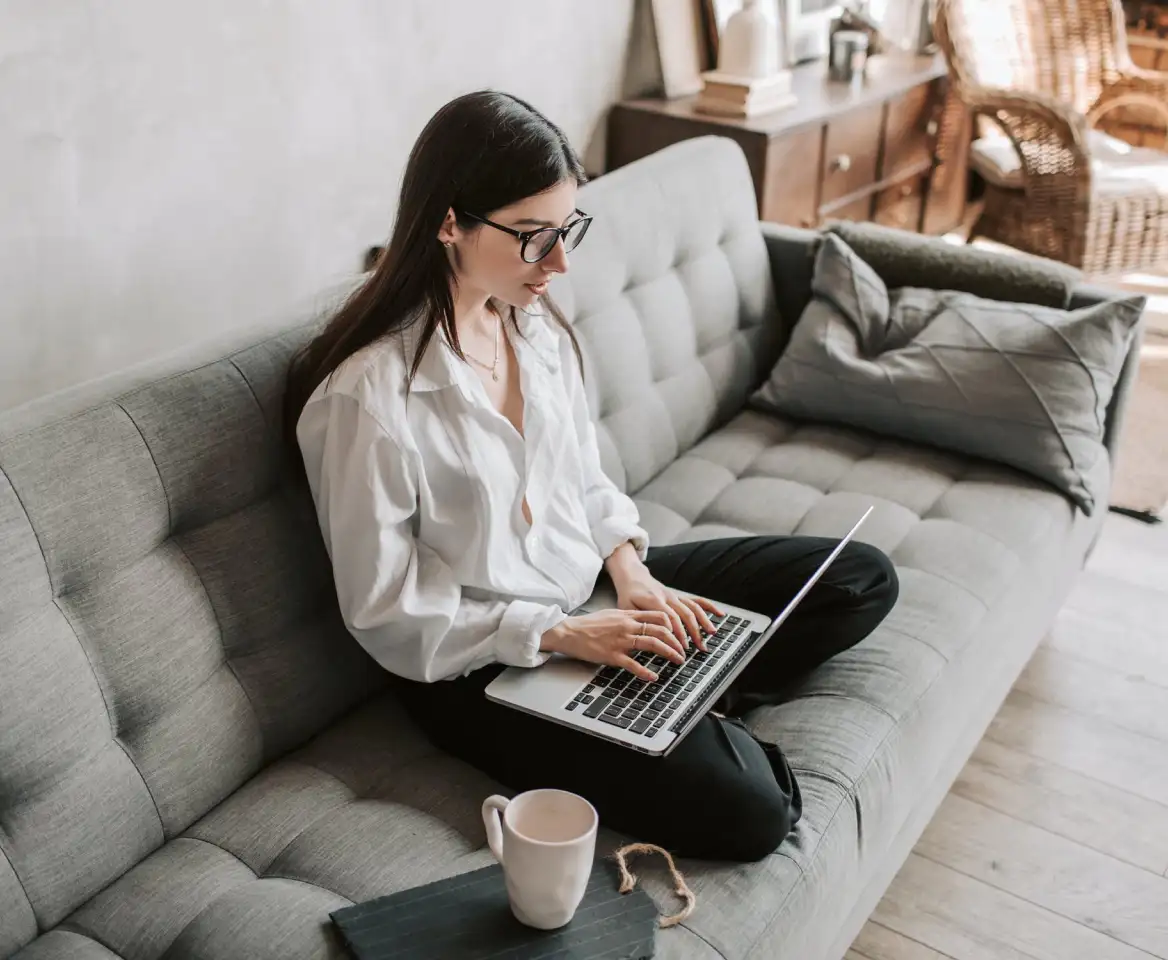 the girl is sitting at the laptop on the couch