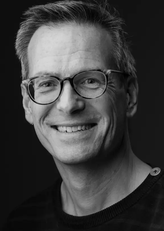 a man in glasses smiles