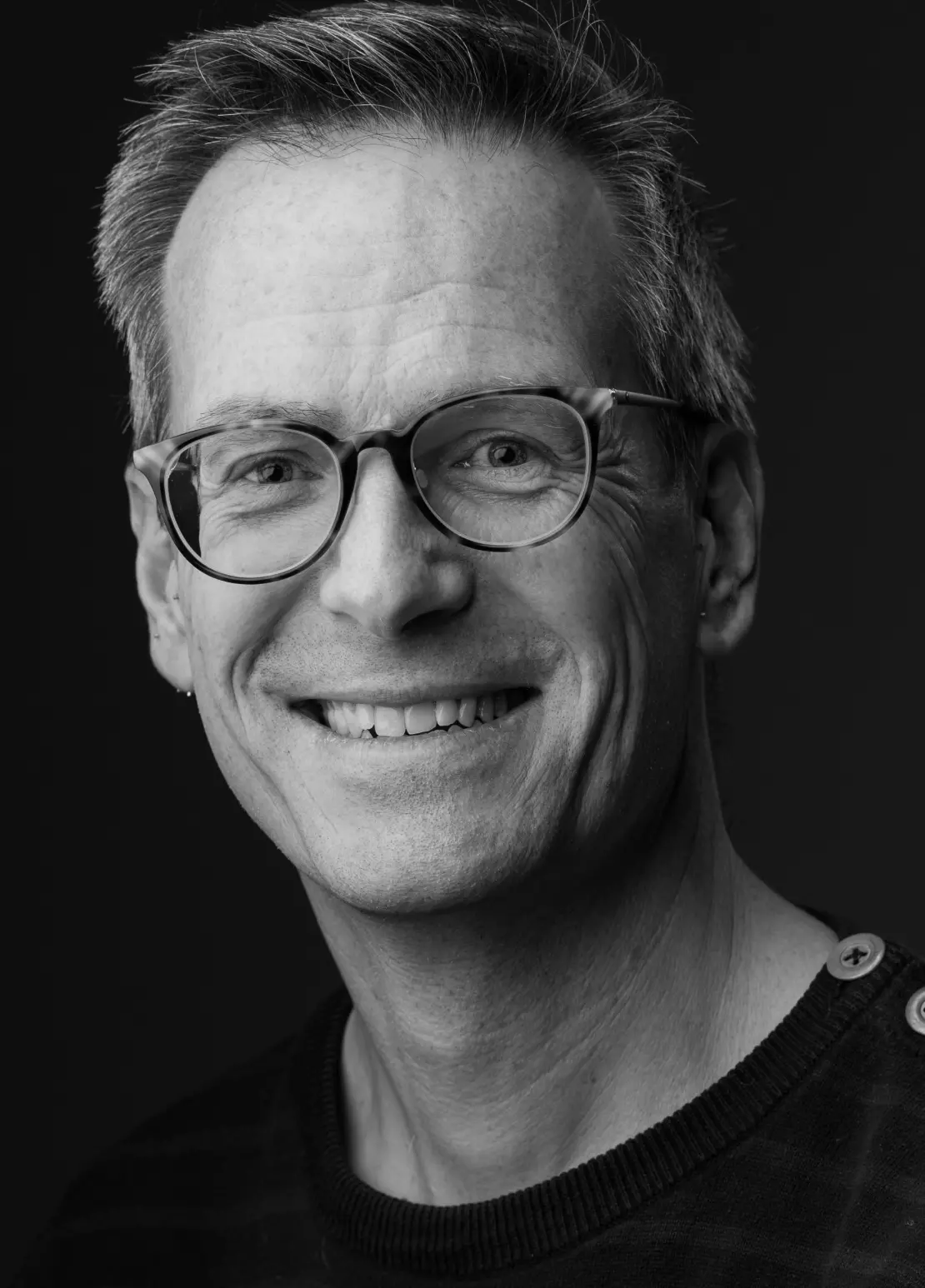 a man in glasses smiles