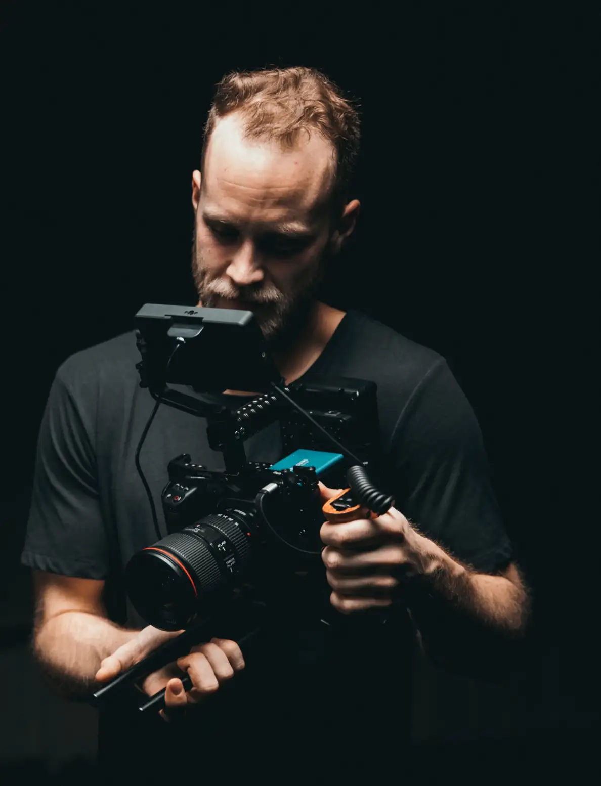 muž v temné místnosti se dívá na svůj fotoaparát, aby zhodnotil pořízené záběry