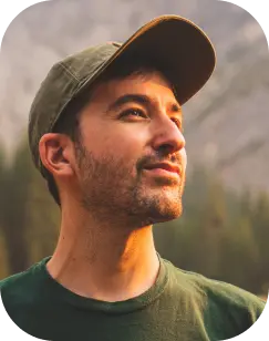 a white man with facial hair and cap hat looking at the sun