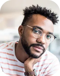 man with short dreadlocks and white shirt wearing glasses and wrist watch