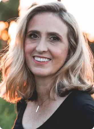 Eine blonde Frau mittleren Alters mit einer Halskette in einem Garten