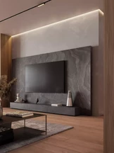 Una sala de estar moderna y luminosa cuenta con un sofá blanco adornado con cojines verdes y grises, flanqueado por dos lámparas blancas y exuberantes plantas.