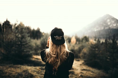 a girl in a cap looks at the forest