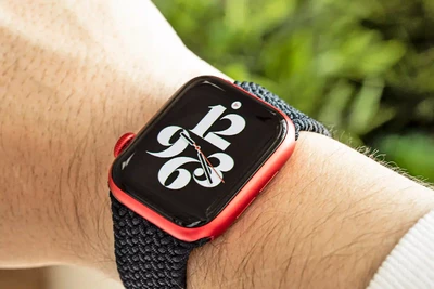 A person wearing a red smartwatch with a bold, black and white digital display showing the time.