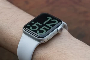 A person wearing a silver smartwatch with a white band, displaying a digital time of 5:51.