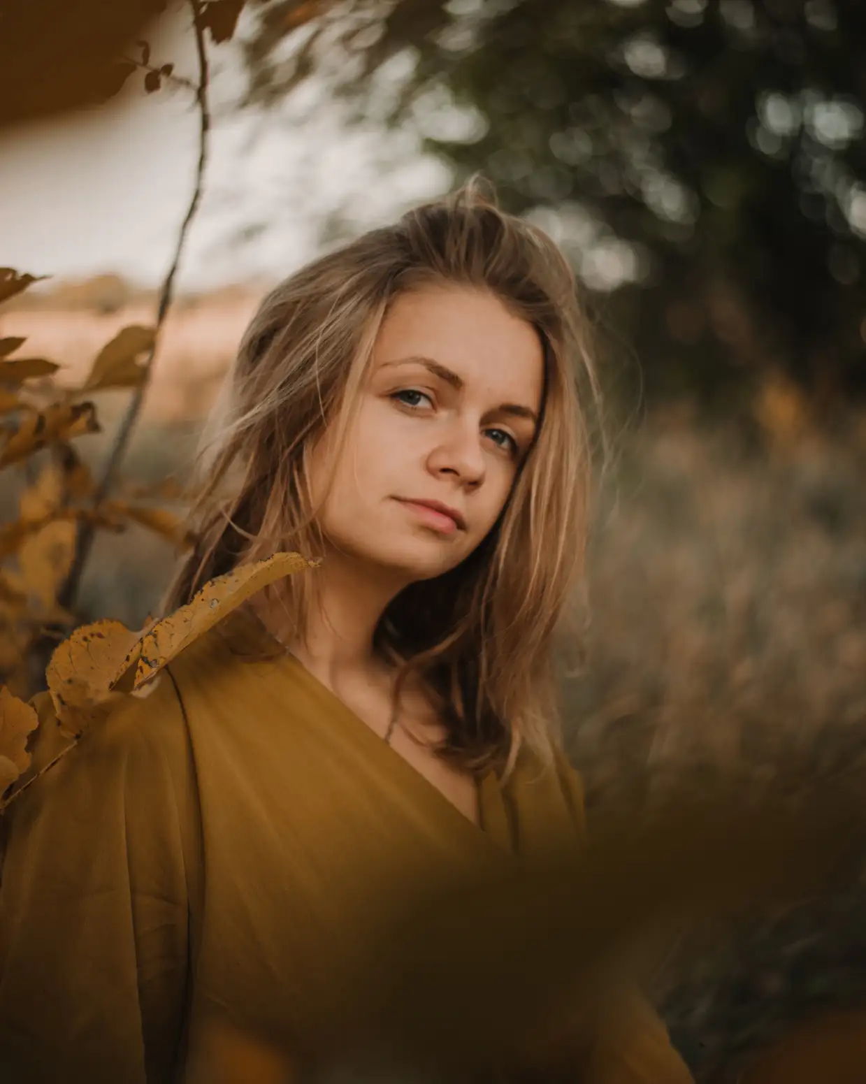 the girl is standing near a tree branch