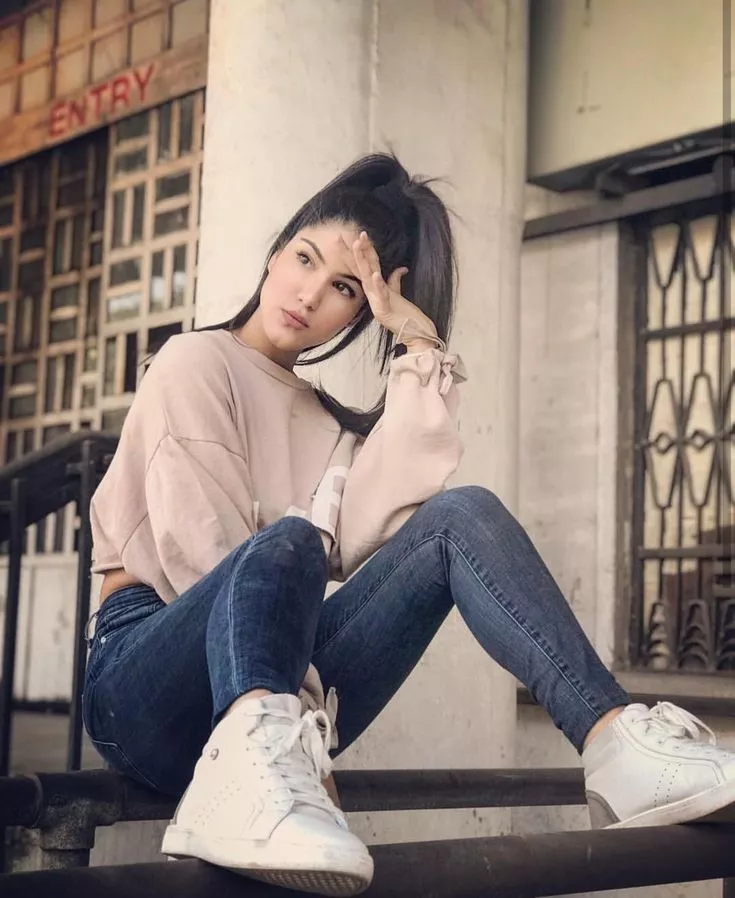 a girl with dark hair holds her head