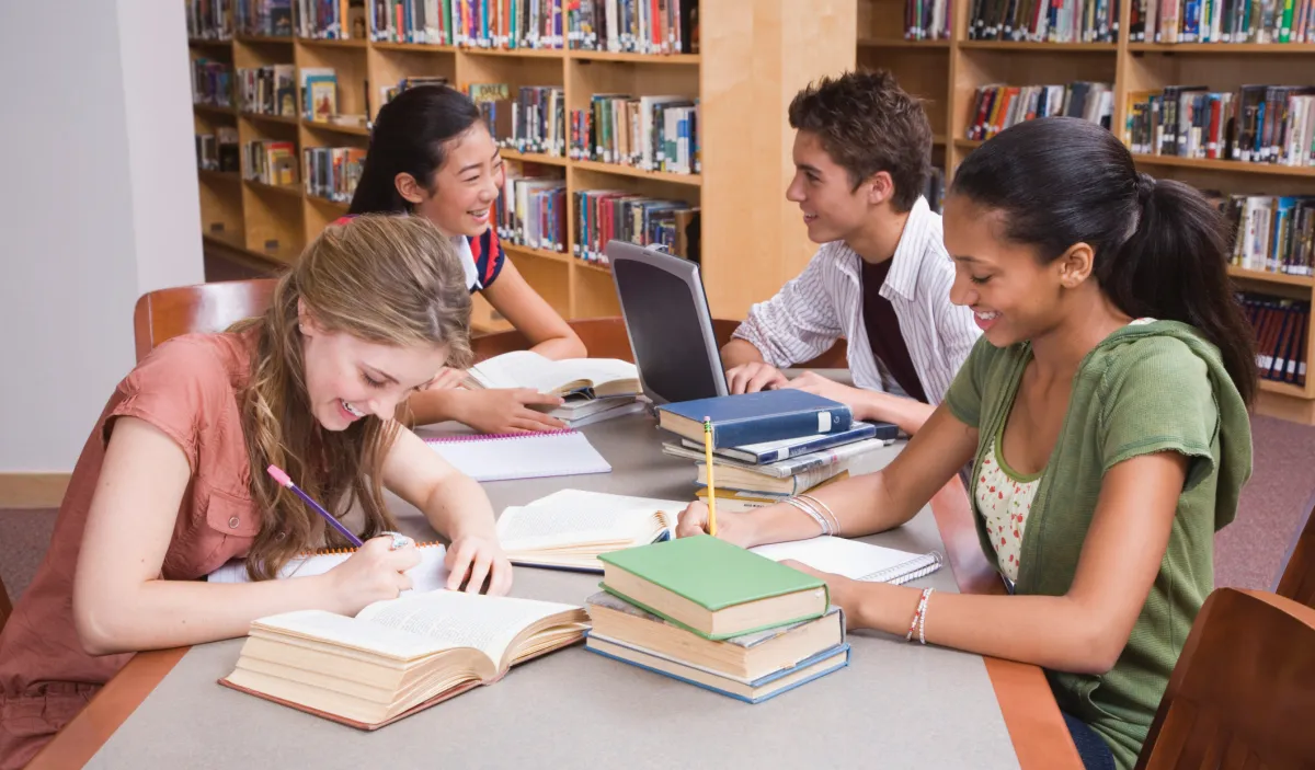 three girls and a boy are studying