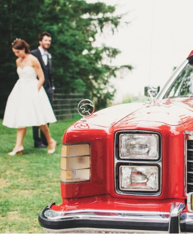 a man and a woman are standing near a red car