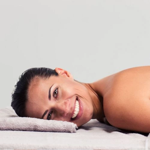 a girl is lying on a massage chair and smiling