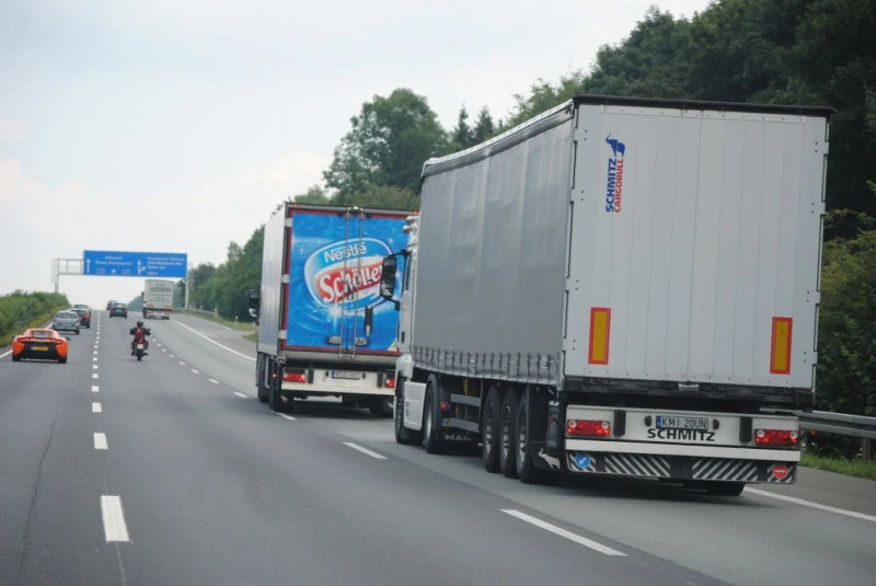two trucks drive down the road