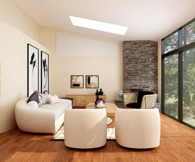 Modernioje svetainėje ant medinių grindų stovi lenkta balta sofa ir du derantys foteliai, o akcentinė siena – akmeninė, o dideli langai atsiveria į žalumą.