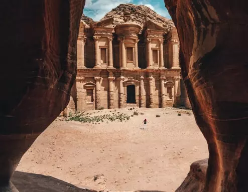 تُظهر الصورة مبنىً قديماً ضخماً بلون رملي. يمكن رؤيته من خلال مدخل كهف. ويظهر شخص في منتصف الصورة.