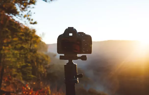 The camera stands on a tripod and is pointed at the sun
