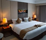 A cozy hotel room features a large bed with crisp white linens and brown accent pillows.