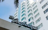 The image shows the exterior of a modern white building with multiple windows, featuring a prominent sign reading 