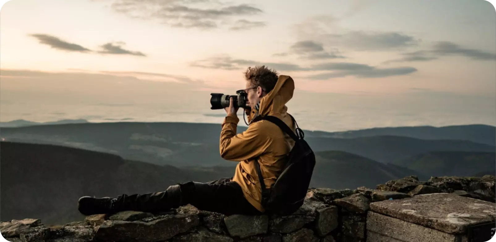 Ein Mann sitzt auf einem Berg und macht Fotos