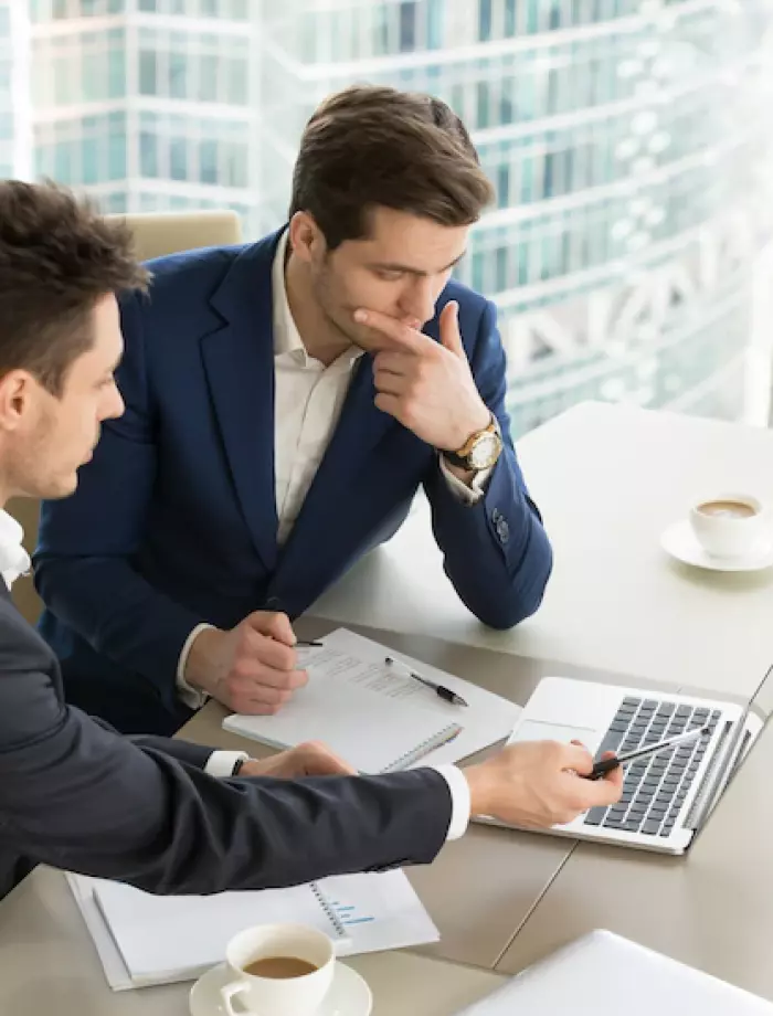 dos hombres sentados frente a una computadora portátil
