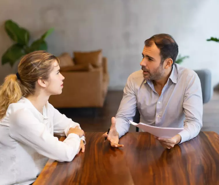 Un hombre y una mujer hablando en la mesa.