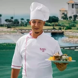طاهٍ يرتدي زيًا أبيض وقبعة يقف في الهواء الطلق
