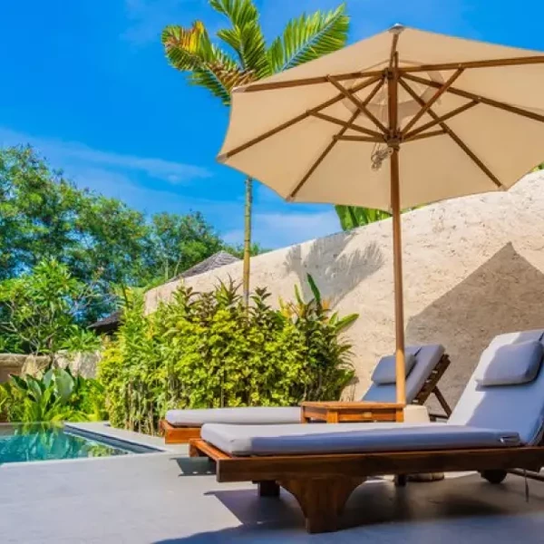 Tropický resort s lehátky, slunečníkem, bazénem a palmami