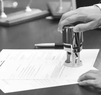 Ein Mann mit einem Stempel in der Hand stempelt ein Dokument ab.