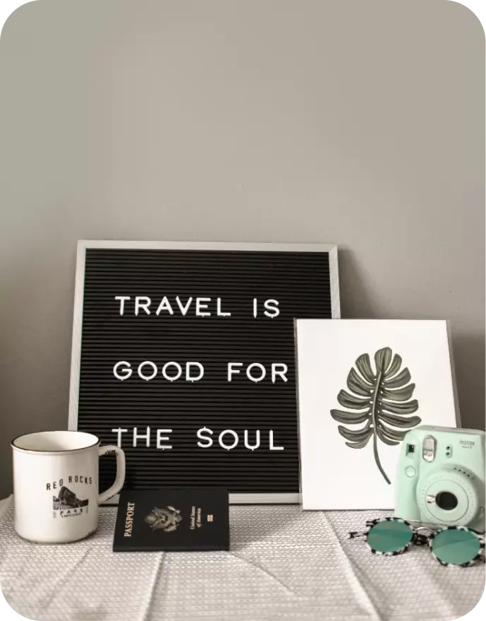 Cosas de viajero sobre la mesa: una taza, una cámara y un pasaporte