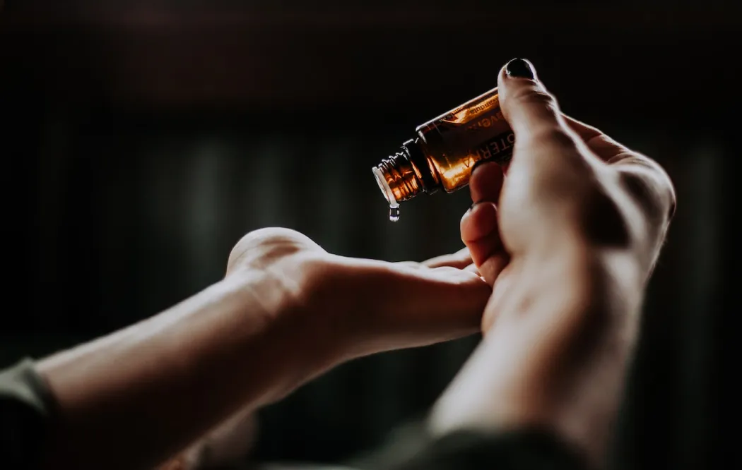a man holds a vessel with oil and pours it on his hand