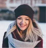 blonde in a black hat with a sincere smile