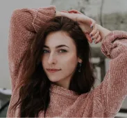 A brown-haired woman in a pink jacket raised her hands above her head