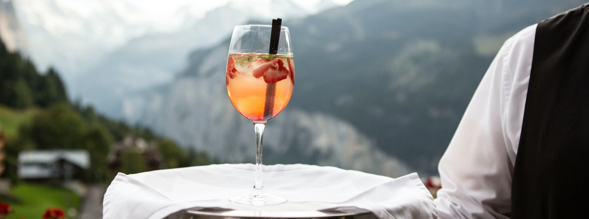Ein Glas auf einem Tablett vor einer Bergkulisse
