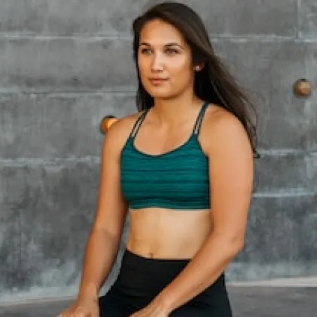 girl with dumbbells in a dark room in the rays of light