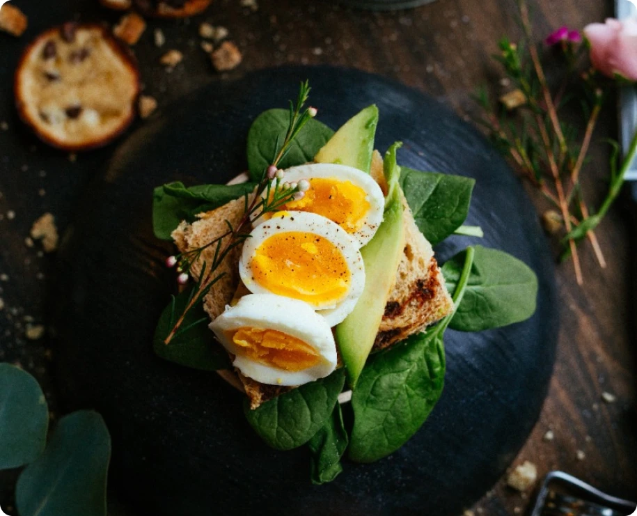Petit-déjeuner composé d'œufs, de légumes et de sablés sur une assiette noire