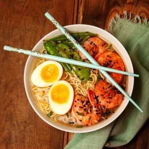 Ramen bowl with boiled eggs, shrimp, green onions, and chopsticks
