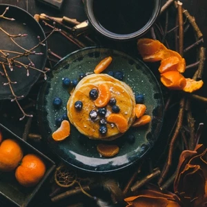 Pancakes with blueberries and syrup, accompanied by coffee and oranges