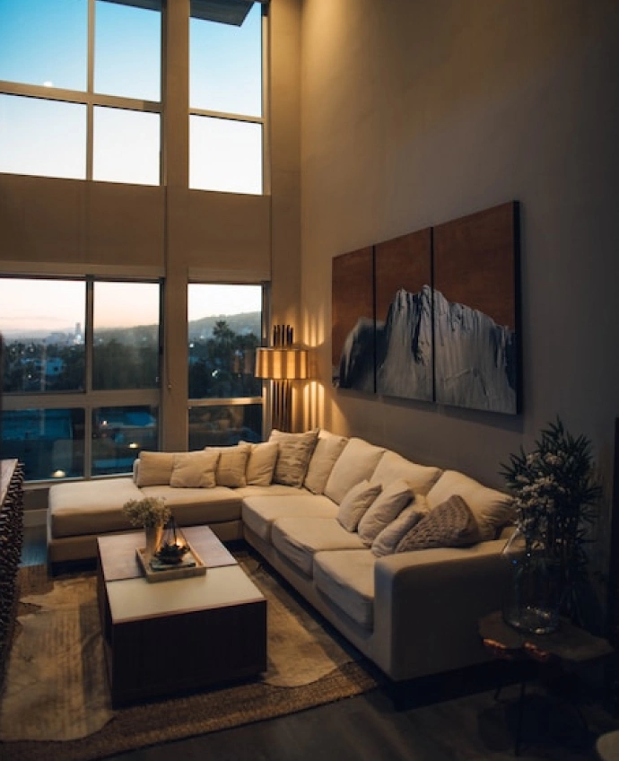 erdvi svetainė su didžiule kampine sofa ir dideliais panoraminiais langais