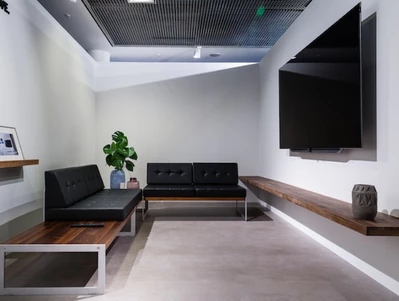 Moderni svetainė su juoda sofa, mediniu kavos staliuku, plokščiaekraniu televizoriumi ir vazoniniu augalu