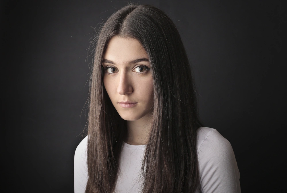Zrzavá dívka se sestříhanými vlasy a konopím na tváři se široce usmívá