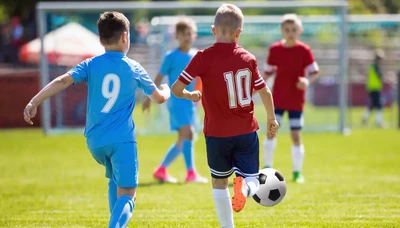 Two young soccer players, one in a red jersey with the number 10 and the other in a blue jersey with the number 9