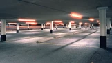 A dimly lit underground parking garage with numerous white columns and empty parking spaces