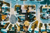 An aerial view of a suburban neighborhood shows a collection of houses with varied roof colors
