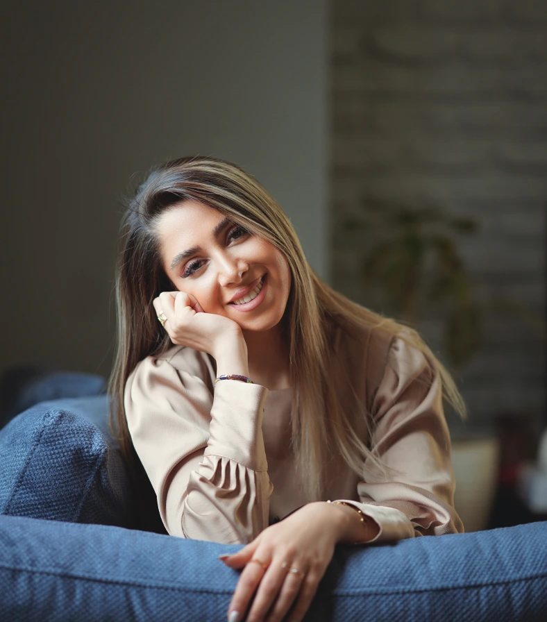 Una chica de cabello castaño con mechones blancos sonríe con la cabeza inclinada.