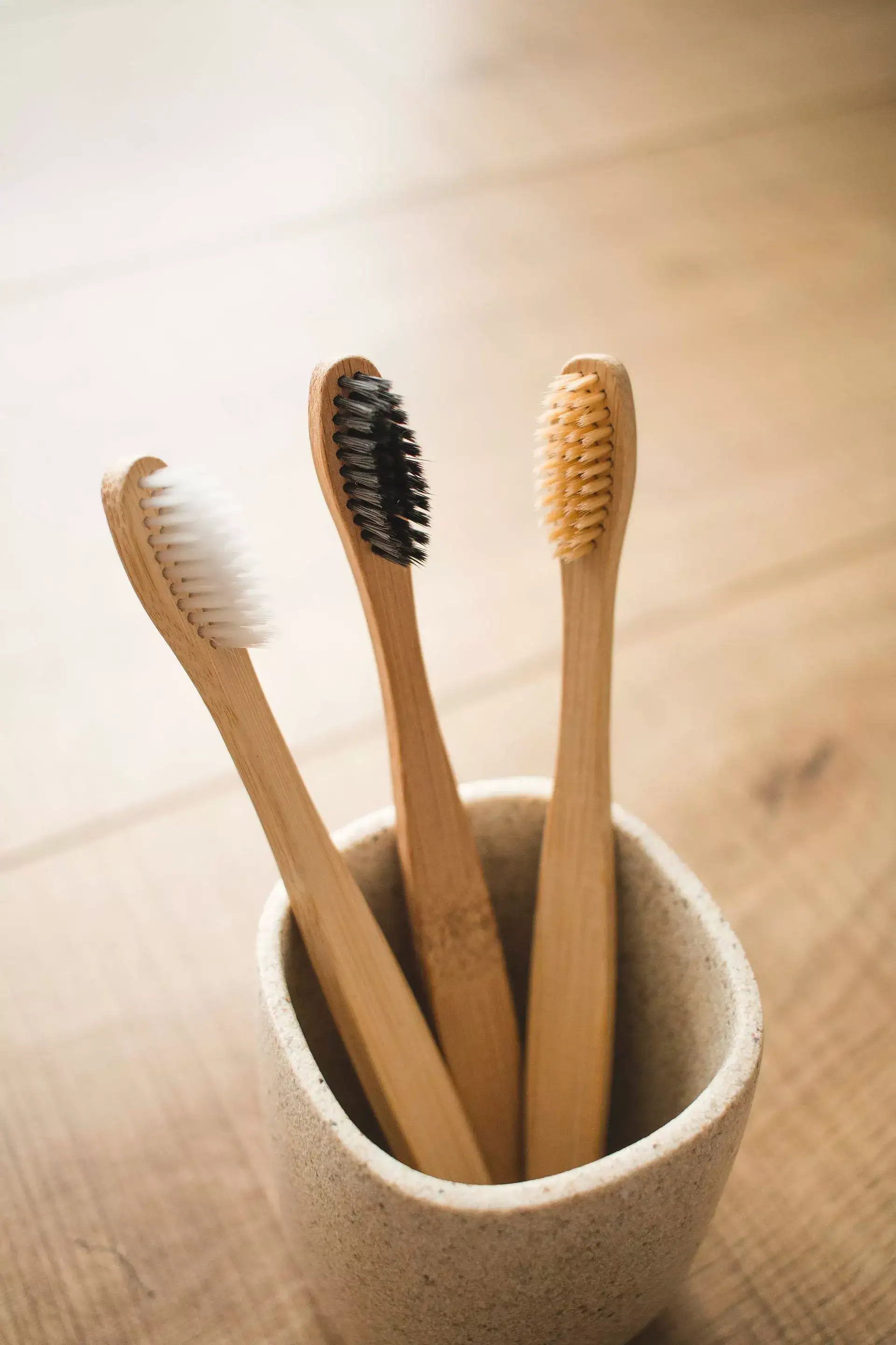 tres cepillos de dientes en un vaso blanco