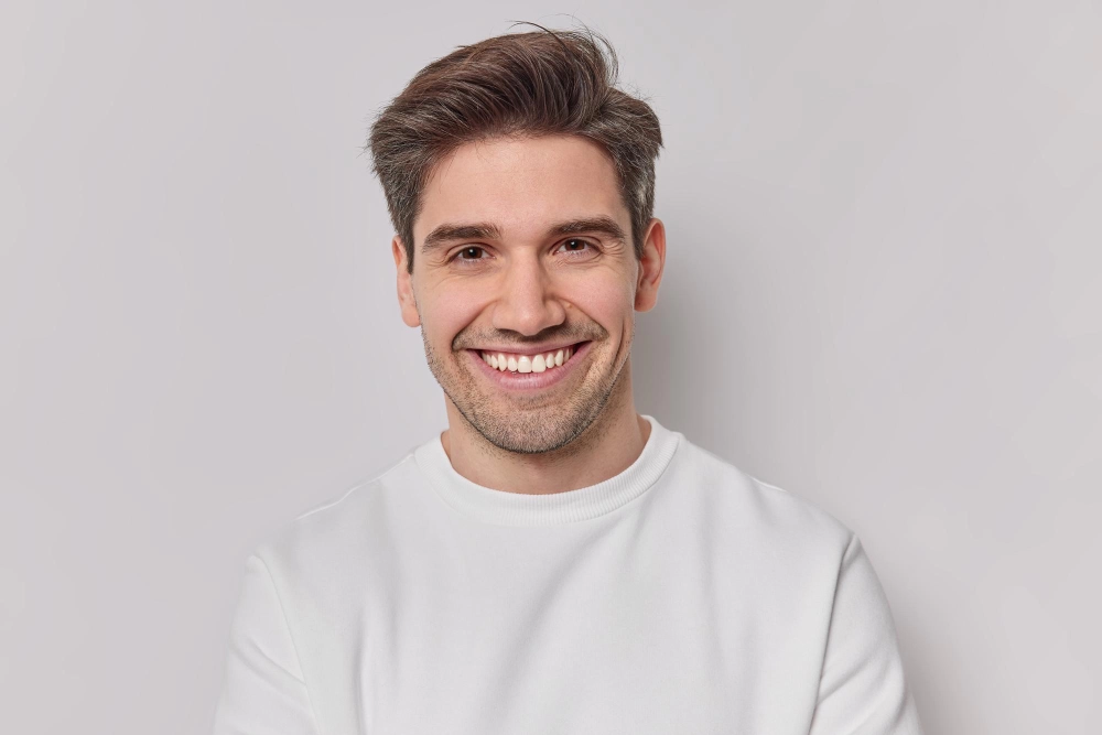 Un hombre con cabello gris sonríe ampliamente.