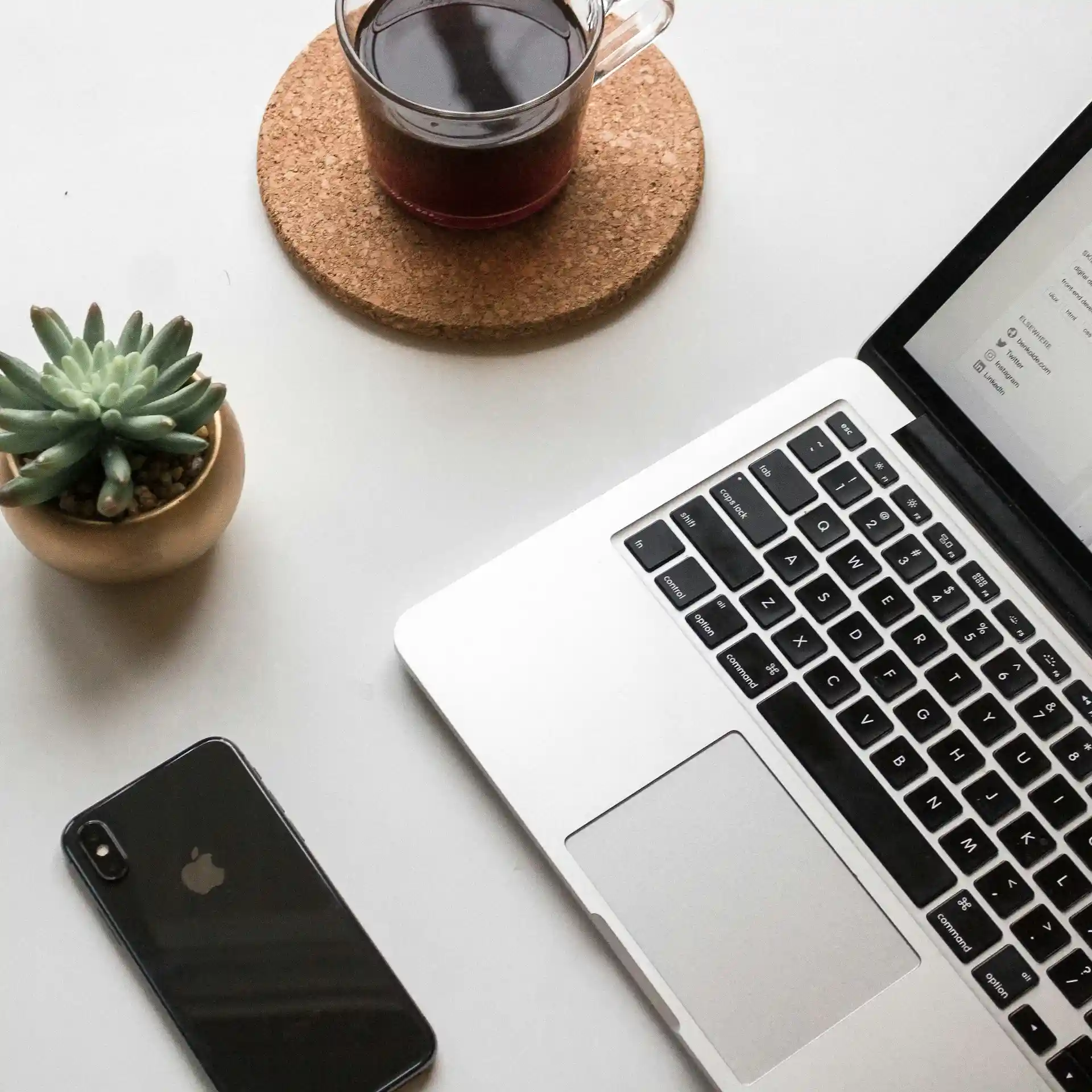 Lugar de trabajo con computadora portátil, flor, teléfono inteligente y taza de té.
