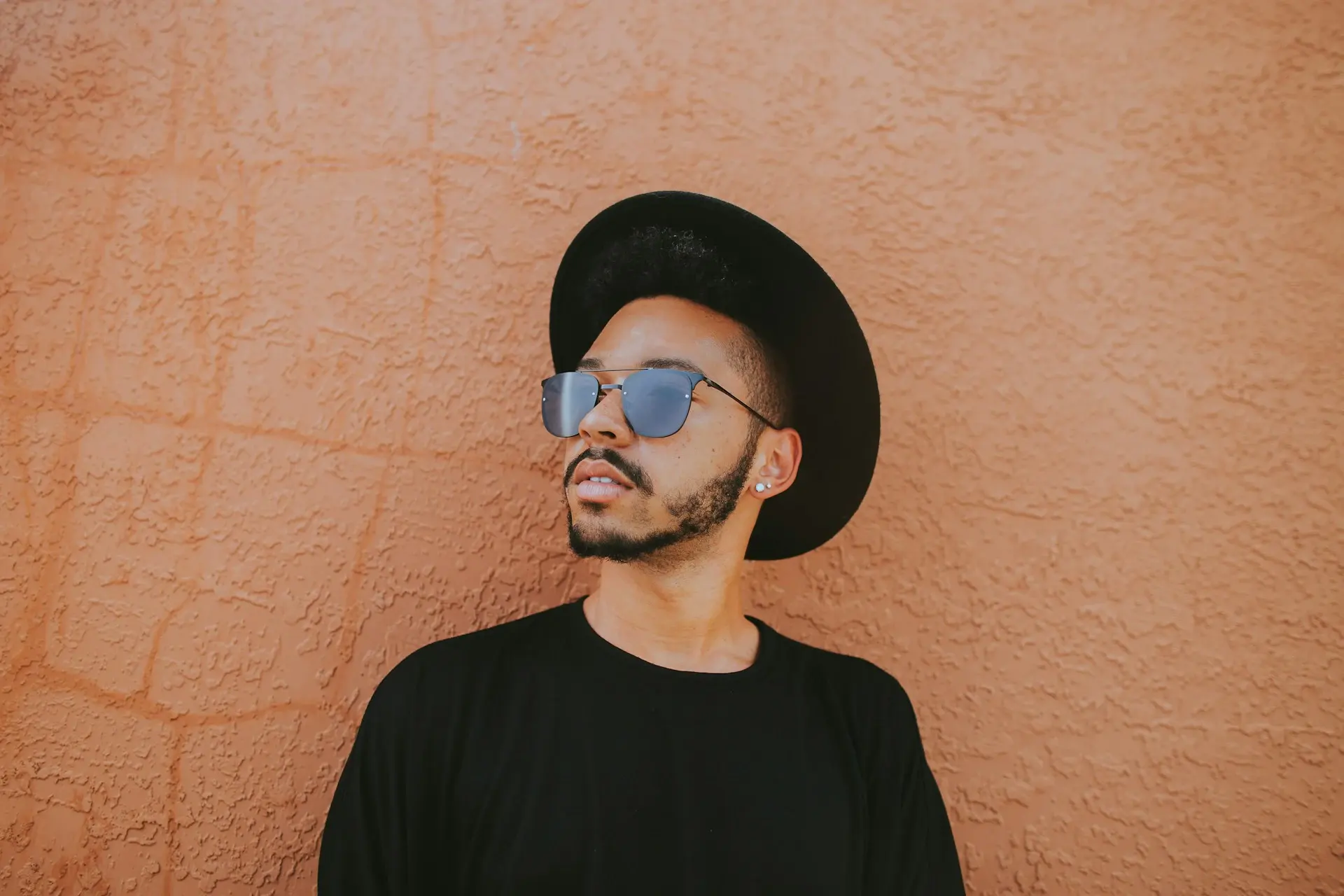 Un chico joven con gafas y un sombrero negro con un escudo en la cara.